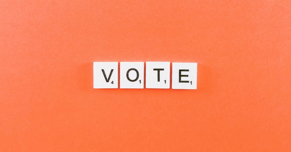 Scrabble letters spelling the word VOTE on an orange background